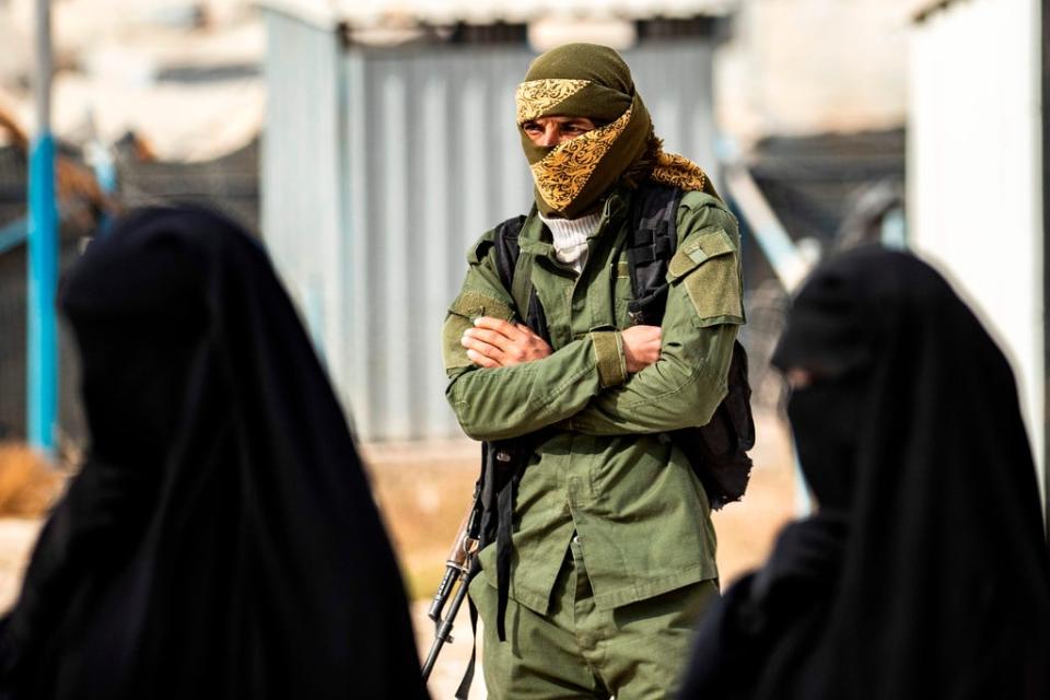 A Kurdish fighter stands guard as Syrian women, suspected of being related to Isis, gather at the al-Hol camp (AFP/Getty)