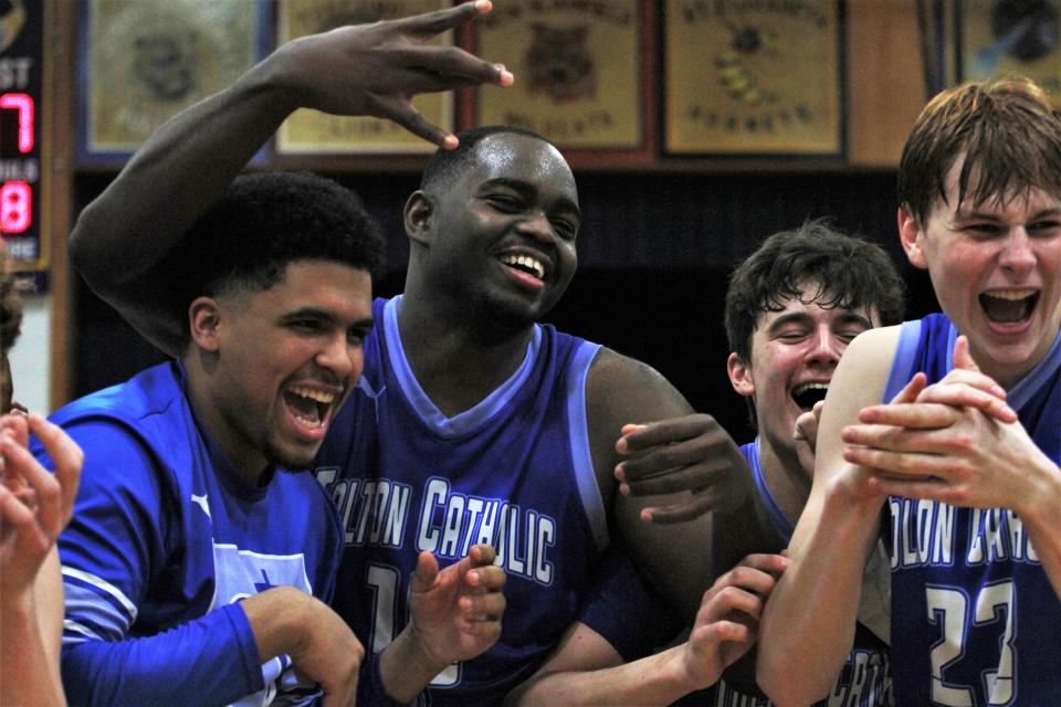 Evens Appolon (center) celebrates with the Father Tolton basketball team after winning the Class 4 District 9 championship game on March 3, 2023, in Westphalia, Mo.