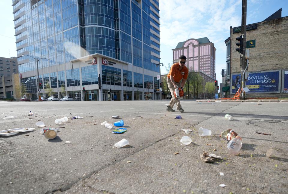 Victor Prado, with MKE Downtown, clears debris near the corner of North Water Street and East Juneau Avenue in Milwaukee on Saturday, May 14, 2022 where seventeen people, ranging in age from 15 to 47, were shot and injured late Friday in Milwaukee's downtown bar districtÂ after the Milwaukee Bucks playoff game.