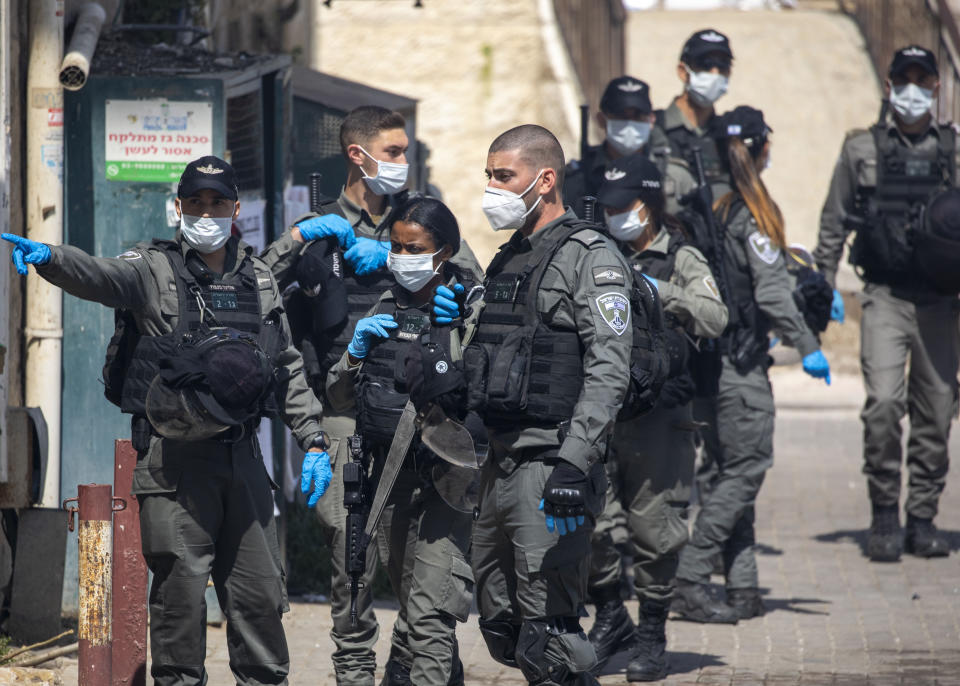 Israeli border police officers wearing face mask gather after dispersing ultra-Orthodox Jewish children burning leavened items in final preparation for the Passover holiday in the Orthodox neighborhood of Mea Shearim in Jerusalem, Wednesday, April 8, 2020. Jerusalem authorities have said they will gather the bread and burn it in a big bonfire in one location to avoid large gatherings. But, some in the Mea Shearim neighbourhood shunned the orders. Many of Israel's ultra-Orthodox residents, obeying their religious leaders, have ignored pleas to stay home in the face of the coronavirus threat. (AP Photo/Ariel Schalit)