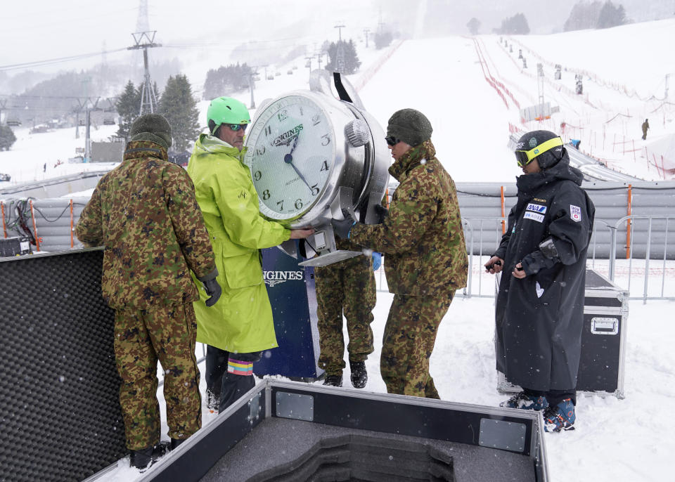 Japan Self-Defense Forces members and event staff put away a clock after it was announced that the men's slalom race has been cancelled due to weather conditions during the FIS Alpine Ski World Cup at Naeba Ski Resort in Yuzawa, Niigata prefecture, northern Japan, Sunday, Feb. 23, 2020. (AP Photo/Christopher Jue)
