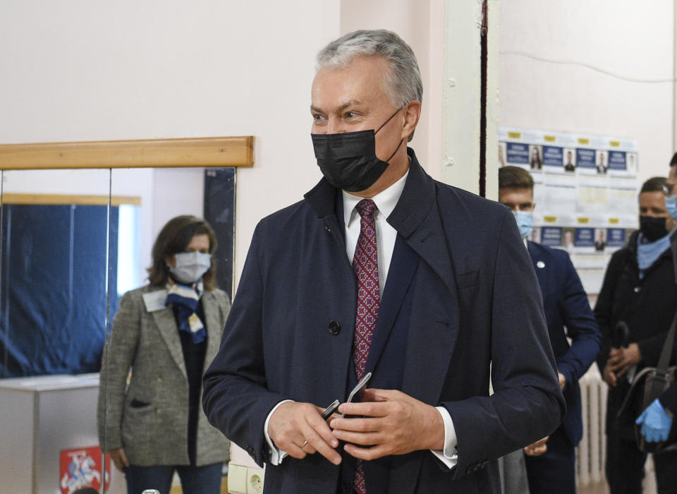 Lithuania's President Gitanas Nauseda, wearing face masks to protect against coronavirus, arrives at a polling station during the parliamentary elections in Vilnius, Lithuania, Sunday, Oct. 11, 2020. Polls opened Sunday for the first round of national election in Lithuania, where voters will renew the 141-seat parliament and the ruling four-party coalition is widely expected to face a stiff challenge from the opposition to remain in office. (Lithuanian President Office via AP)