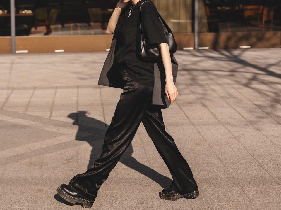 woman walking down the street wearing an all black outfit with black accessories