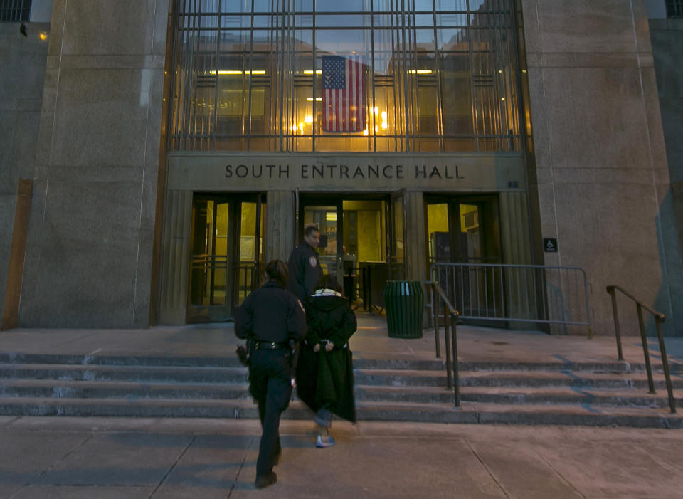 Two police officers escort a handcuffed woman into New York's Criminal Court Building, Tuesday evening, March 11, 2014. Night court is one of New York’s more peculiar and paradoxical tourist traditions, a place visitors extol on travel websites while many residents hope never to wind up there. To travelers, it’s gritty entertainment, hard-knocks education or at least a chance to experience real-life law and order on a New York scale. (AP Photo/Richard Drew)