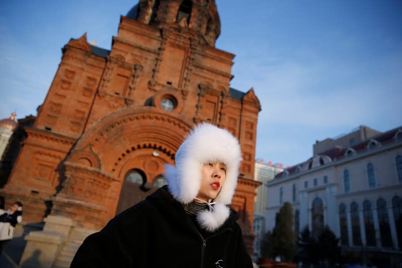 A woman stands in front of the Saint Sophia Cathedral in Harbin