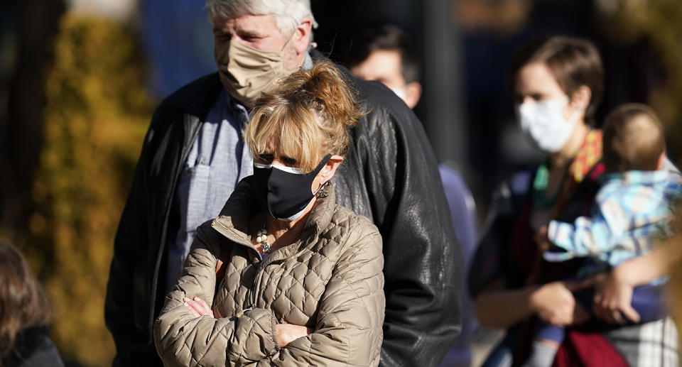 Concerned man and woman shown on the street in surgical masks.