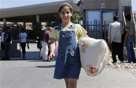 A Syrian refugee girl carries her pillow as she enters Turkey from the Turkish Cilvegozu border gate, located opposite the Syrian commercial crossing point of Bab al-Hawa, in Reyhanli, Hatay province, September 11, 2013. REUTERS/Umit Bektas