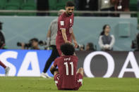 Qatar's Hassan Al-Haydos helps Akram Afif stand up after the World Cup group A soccer match between Qatar and Senegal, at the Al Thumama Stadium in Doha, Qatar, Friday, Nov. 25, 2022. Senegal won 3-1. (AP Photo/Hassan Ammar)