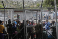 In this Wednesday, Sept. 25, 2019 photo, people wait outside the information office at a refugee and migrant camp of the Greek island of Samos. Greece's conservative government announced Wednesday Nov. 20, 2019, plans to overhaul the country's migration management system, and replacing existing camps on the islands with detention facilities and moving and 20,000 asylum seekers to the mainland over the next few weeks. (AP Photo/Petros Giannakouris)