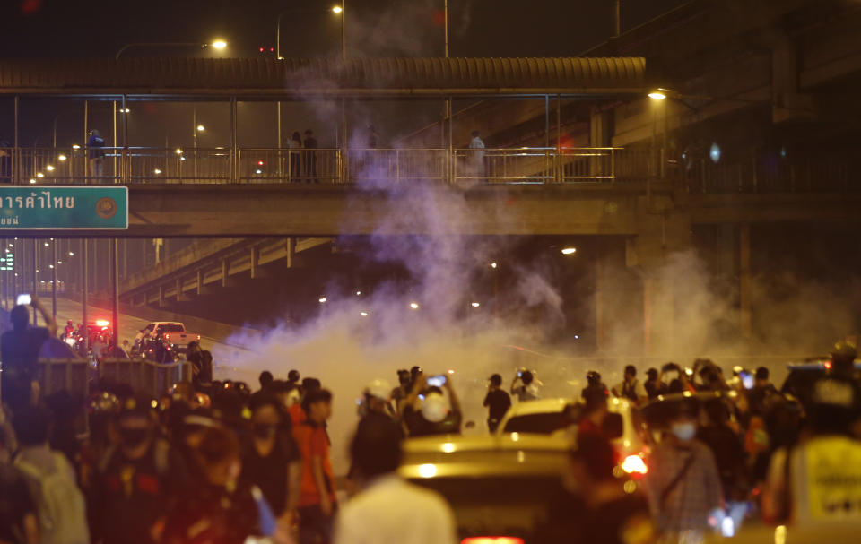 Riot policemen shoot tear gas on the road near to anti-government protesters, during a protest in Bangkok, Thailand, Sunday, Feb. 28, 2021. The anti-government protesters marched towards a military house where Prime Minister Prayuth Chan-ocha lives to call for monarchy reform and the military removal from the politics. (AP Photo)