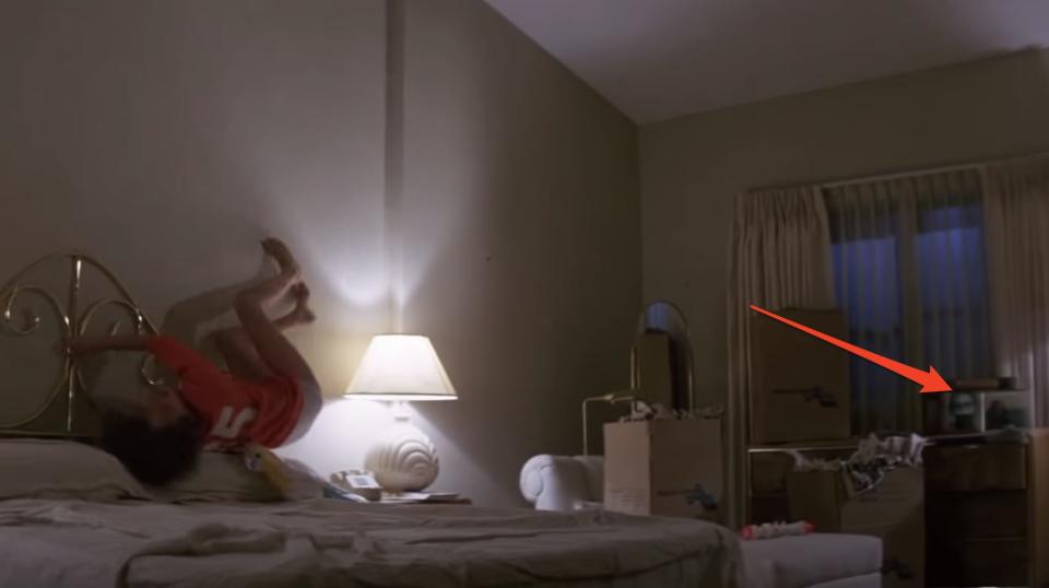 woman climbing the walls in "Poltergeist" with a picture frame with a ghost pointed out