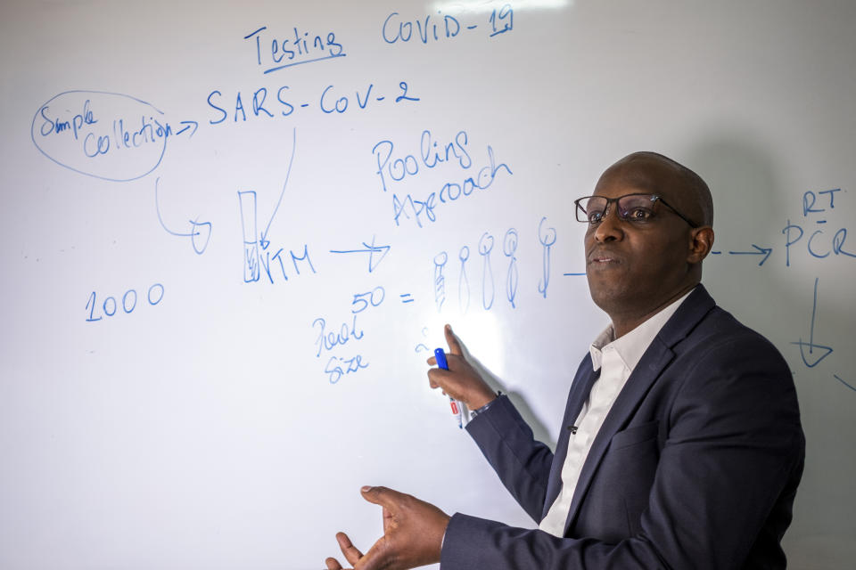 Rwandan professor of human genetics and a member of the government's COVID-19 task force, Leon Mutesa, explains the pooled testing procedures for the coronavirus as he speaks to The Associated Press at the Rwanda Biomedical Center in the capital Kigali, Rwanda, Tuesday, July 28, 2020. Like many countries, Rwanda is finding it impossible to test each of its citizens for the coronavirus amid shortages of supplies but researchers there have created an innovative approach using an algorithm to refine the process of pooled testing that's drawing attention beyond the African continent. (AP Photo)