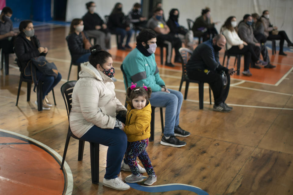 People sit socially distanced inside a gym before getting a shot of the Sinopharm COVID-19 vaccine on the outskirts of Buenos Aires, Argentina, Friday, July 9, 2021, as authorities speed up vaccinations after a slow start. (AP Photo/Victor R. Caivano)