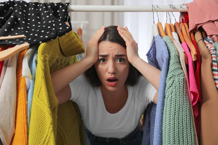 woman putting her hands on her head surrounded by clothing racks