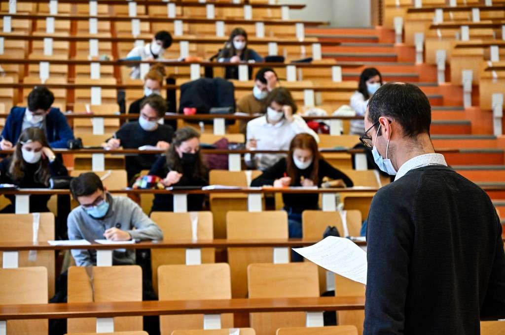 University of Rennes 1 students, wearing protective nose and mouth masks to curb the spread of the novel coronavirus, Covid-19, sit in an auditorium as they attend a supervised physics lecture in Rennes, western France on January 4, 2021. (Photo by Damien MEYER / AFP)