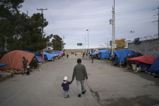 A man walks with his daugher at an asylum seekers camp near the Zaragoza bridge in Ciudad Juarez, Mexico