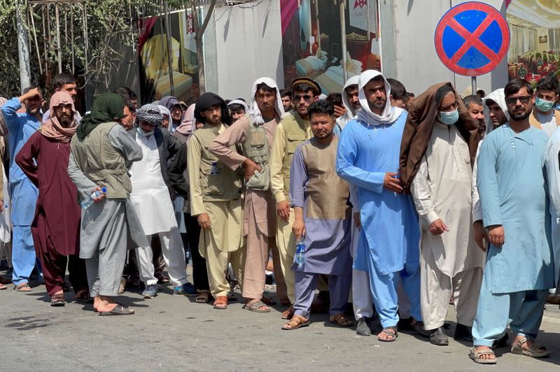 FILE PHOTO: Afghans line up outside a bank to take out their money after Taliban takeover in Kabul