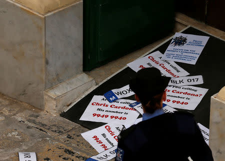 A police officer looks at posters left by civil society activists calling on the police to question Maltese Economy Minister Chris Cardona, after some of the journalists from the Daphne Project initiative reported him as having met with one of the men accused of the murder of anti-corruption journalist Daphne Caruana Galizia, at the police station in Valletta, Malta April 19, 2018. REUTERS/Darrin Zammit Lupi
