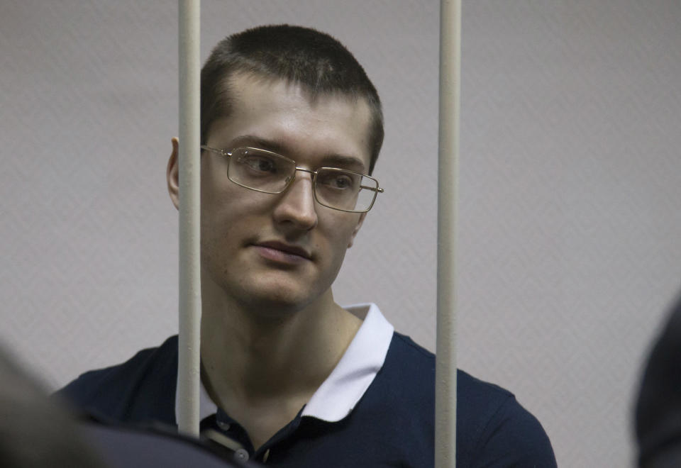 ADDS NAME OF DEFENDANT Opposition activist Yaroslav Belousov stands behind bars in a cage at a court room in Moscow, Russia, Monday, Feb. 24, 2014, where hearings started against opposition activists detained on May 6, 2012 during a rally at Bolotnaya Square. A Moscow judge on Friday, Feb. 21, 2014, convicted eight anti-government protesters of rioting during a 2012 protest against Vladimir Putin, following a trial seen as part of the Kremlin's efforts to stifle dissent. (AP Photo/Alexander Zemlianichenko)