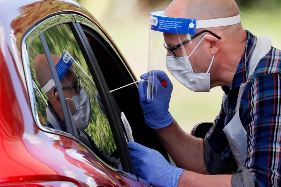 A medical worker takes a swab to test for the novel coronavirus COVID-19 from a visitor to a drive-in testing facility at the Chessington World of Adventures Resort, in Chessington, southwest of London, on May 2, 2020. - Britain's overall death toll from the coronavirus outbreak rose by 739 to 27,510 on May 1 as the government announced that it had reached its COVID-19 testing goal administering a total of 122,347 tests on April 29. (Photo by Adrian DENNIS / AFP) (Photo by ADRIAN DENNIS/AFP via Getty Images)