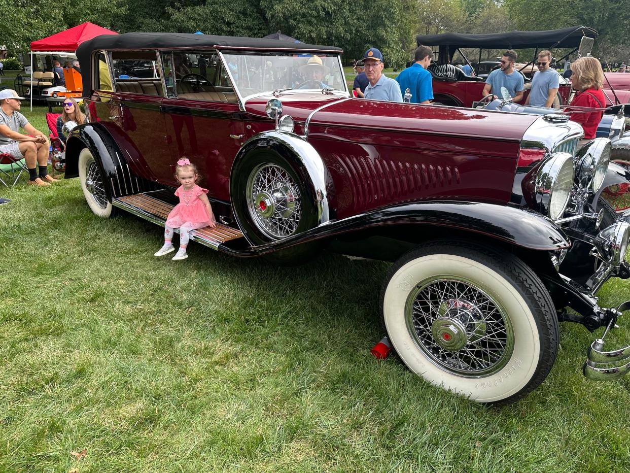 Arianna Smith sits on the side of a 1930 Model J Duesenberg on display at Stan Hywet Hall & Gardens during the La Machine Molto Bella car show on Sept. 10 in Akron.