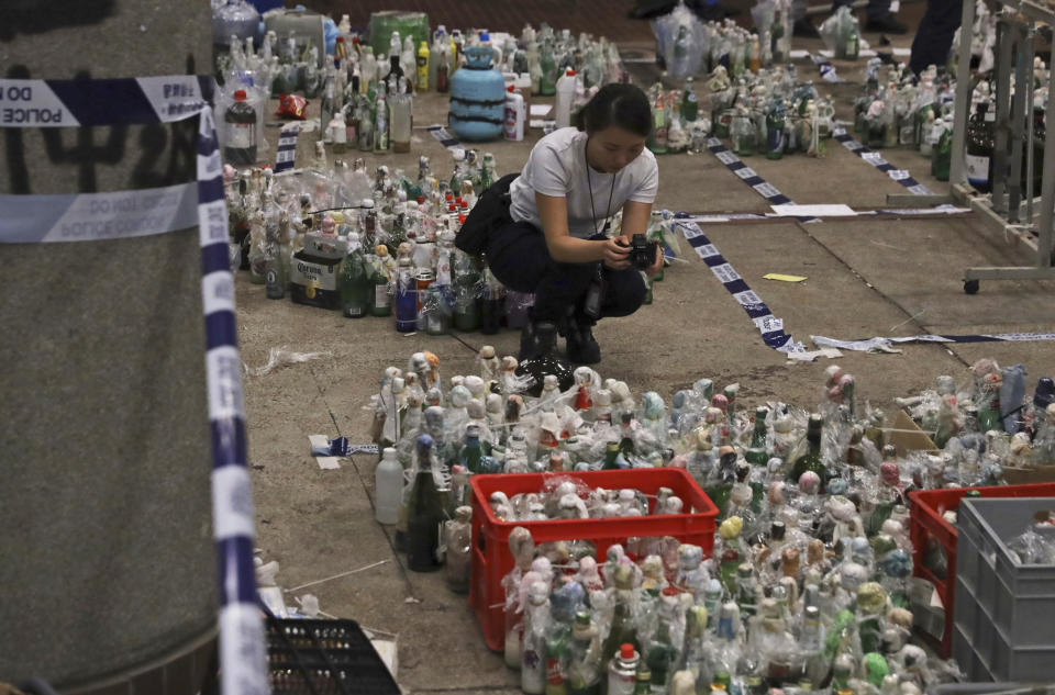 A policewoman takes photographs of gas canisters and flammable material as evidence in a cordoned off area in the Polytechnic University campus in Hong Kong, Thursday, Nov. 28, 2019. Police safety teams Thursday began clearing a university that was a flashpoint for clashes with protesters, and an officer said any holdouts still hiding inside would not be immediately arrested. (AP Photo/Ng Han Guan)