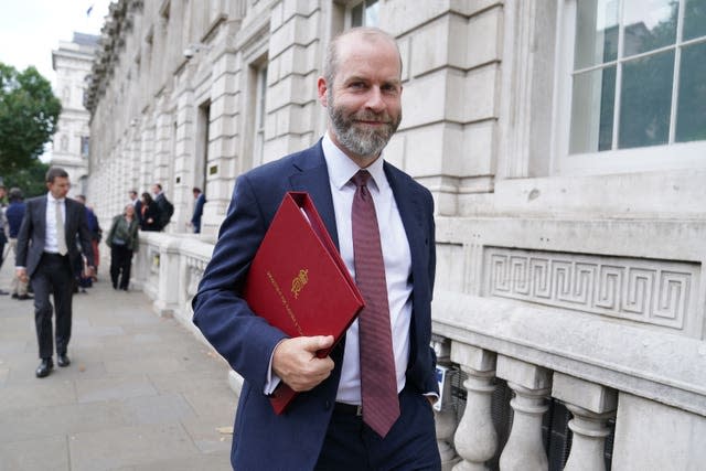 Jonathan Reynolds walking while carrying a red Government folder under his arm