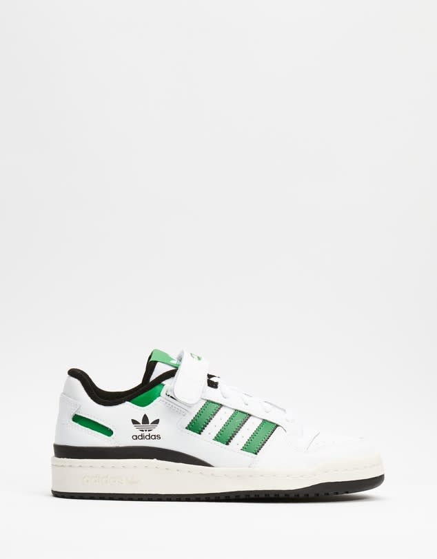 A pair of classic retro Adidas sneakers in white with black and green highlights