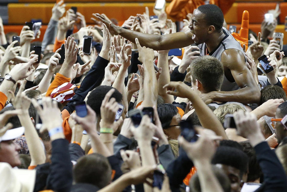 Oklahoma State wing Markel Brown, upper right, celebrates with fans following an NCAA college basketball game against Kansas in Stillwater, Okla., Saturday, March 1, 2014. Oklahoma State won 72-65. (AP Photo/Sue Ogrocki)