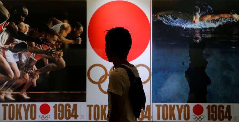 FILE PHOTO: A pedestrian looks at pictures of the 1964 Summer Olympics in Tokyo, inside the Tokyo train station building