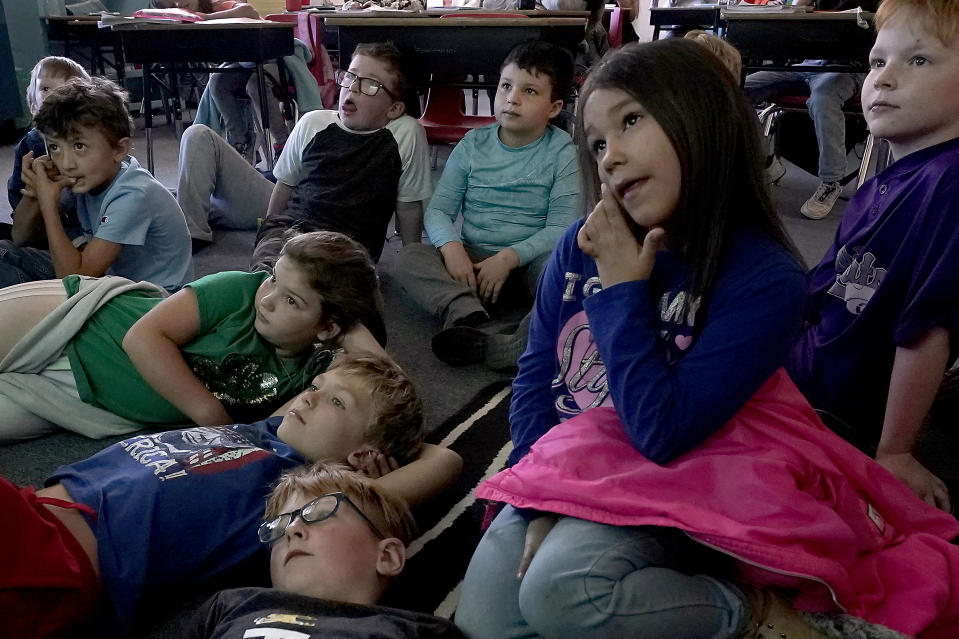 Third-grader Parker, background center, and classmates watch a video at Highland Elementary School in Columbus, Kan., on Monday, Oct. 17, 2022. When the pandemic first closed schools in 2020, Parker was a kindergartener. His mom recalled “freaking out,” trying to figure out what to do with him. To get him to do schoolwork, his grandmother or someone else had to sit beside him at all times. Otherwise, Parker said, he would “squirrel off.” (AP Photo/Charlie Riedel)