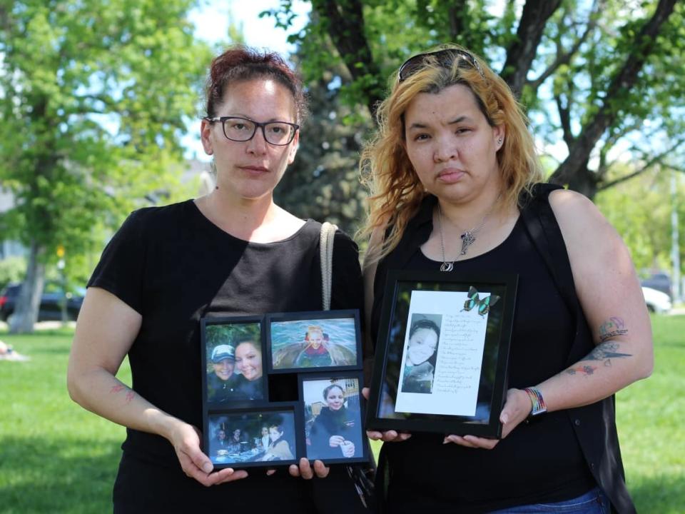 Chrissy Wheeler, left, and Candice Wheeler, right, hold family photos of their middle sister, Courtney, who died in December 2021. The sisters are searching for answers as to why Courtney was buried the next month without their knowledge. (Paula Duhatschek/CBC - image credit)