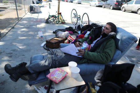 Jimmy Melgar, 33, who has been homeless for 2 years, lies on the reclining chair on which he sleeps in Los Angeles, California, U.S. March 29, 2018. Picture taken March 29, 2018. REUTERS/Lucy Nicholson