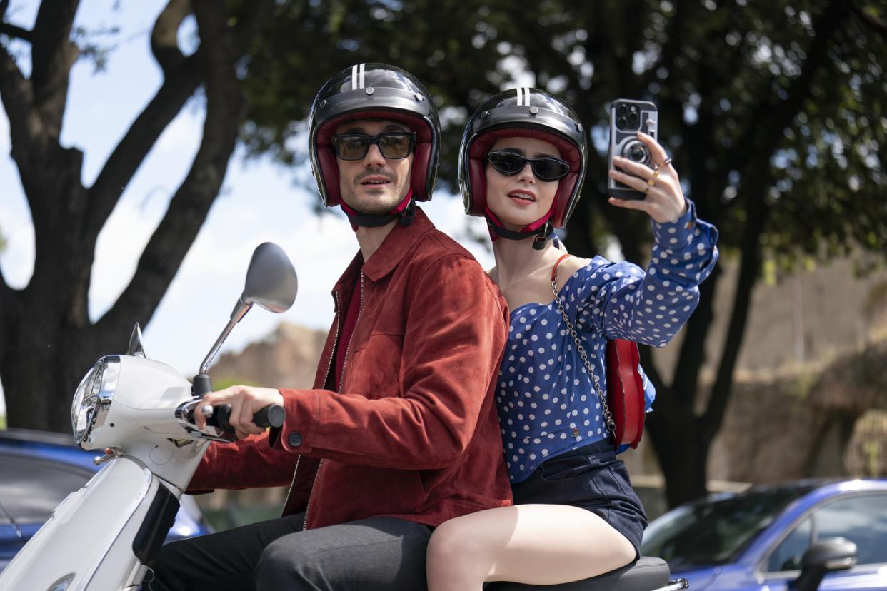 Collins takes a photo with her cellphone as she rides on the back of Franceschini’s scooter.