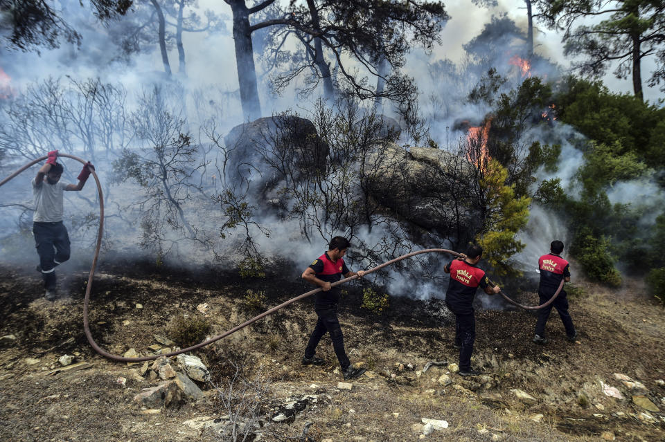 Firefighters work to extinguish a fire in Yatagan of the Mugla province, Turkey, Friday Aug. 6, 2021. Thousands of people fled wildfires burning out of control in Greece and Turkey on Friday, as a protracted heat wave turned forests into tinderboxes that threatened populated areas, electricity installations and historic sites. (Ismail Coskun/IHA via AP)