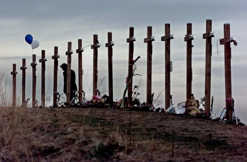 In this April 28, 1999, file photo, a woman stands among 15 crosses posted on a hill above Columbine High School in Littleton, Colo., in remembrance of the 15 people who died during a school shooting on April 20, 1999.