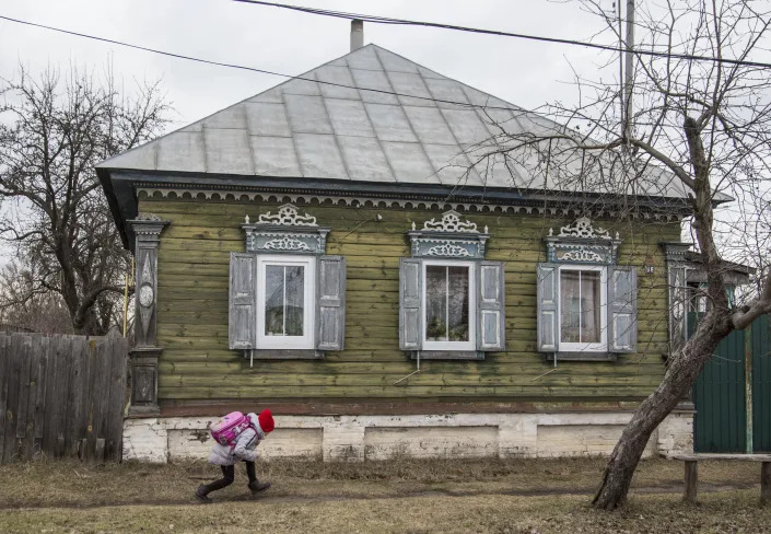 A schoolgirl runs in Ukraine's village of Dobryanka close to the Belarus border, Monday, Feb. 21, 2022. (AP Photo/Oleksandr Ratushniak)