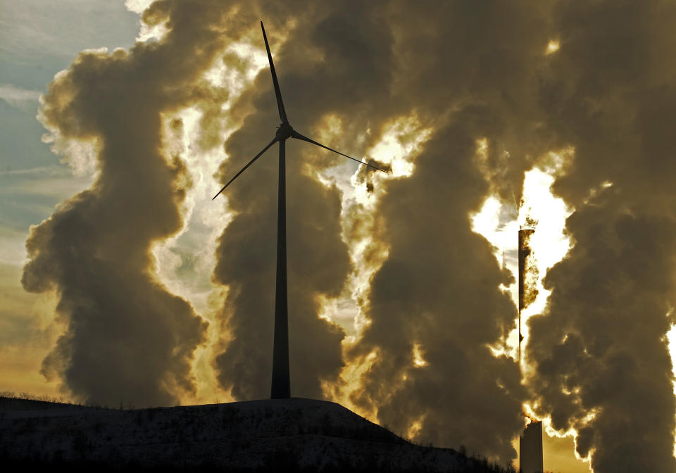 FILE - In this Dec. 6, 2010 file photo a wind turbine is pictured in the in front of a steaming coal power plant in Gelsenkirchen, Germany. The U.N.’s expert panel on climate change is preparing a new report this weekend outlining the cuts in greenhouse gases, mainly CO2 from the burning of fossil fuels, required in coming decades to keep global warming in check.(AP Photo/Martin Meissner, File)