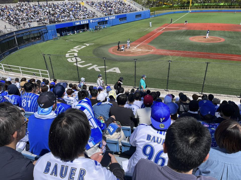 Fans wearing shirts with the name of baseball player Trevor Bauer and his number, watch his pitching at a stadium in Yokosuka, Japan, Sunday, April 16, 2023. Bauer pitched four innings Sunday for the Yokohama BayStars minor league team in Yokosuka as he prepares to pitch his first game for the Yokohama team. (AP Photo/Stephen Wade)