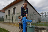 Karmen Bastyur, a 22 year old Hungarian Roma woman, fills a bucket with drinking water from a public water pump in Bodvaszilas, Hungary, Monday, April 12,2021. Many students from Hungary's Roma minority do not have access to computers or the internet and are struggling to keep up with online education during the pandemic. Surveys show that less than half of Roma families in Hungary have cable and mobile internet and 13% have no internet at all. (AP Photo/Laszlo Balogh)