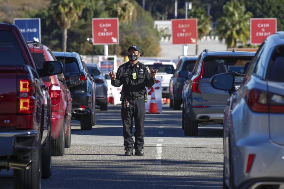 A man in uniform stands between lanes of traffic.