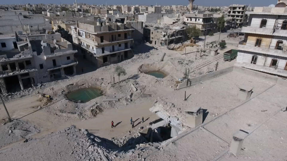 <p>A still image taken on September 27, 2016 from a drone footage obtained by Reuters shows people standing near craters and damaged buildings in a rebel-held area of Aleppo, Syria. (Handout via Reuters)</p>