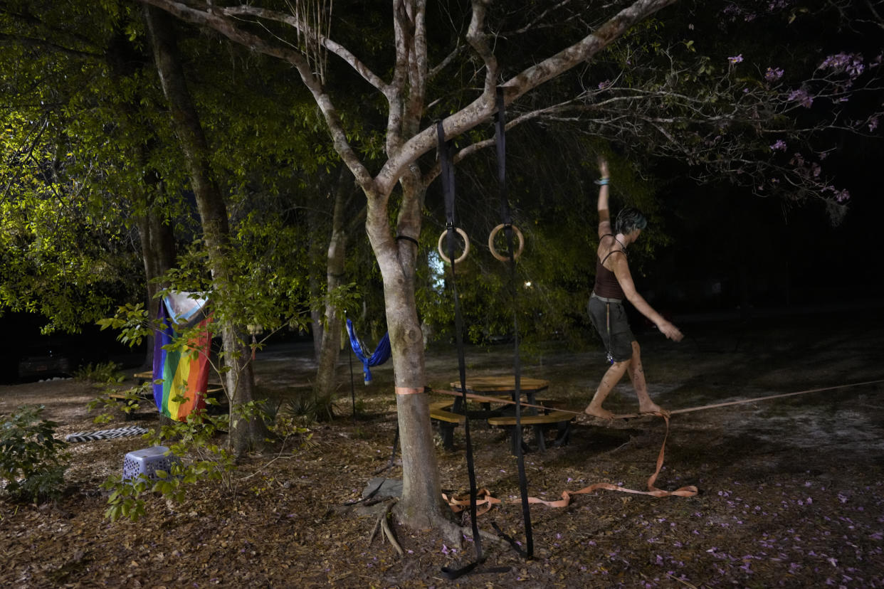 Second-year transfer student Bug Hamnon, 20, walks on a zipline set up outside a dormitory at New College of Florida, Wednesday, March 1, 2023, in Sarasota, Fla. Republican Gov. Ron DeSantis has targeted the tiny school on the shores of Sarasota Bay as a staging ground for his war on "woke," charging that New College, a progressive school with a prominent LGBTQ+ community, is indoctrinating students with leftist ideology and should be revamped into a more conservative institution. (AP Photo/Rebecca Blackwell)