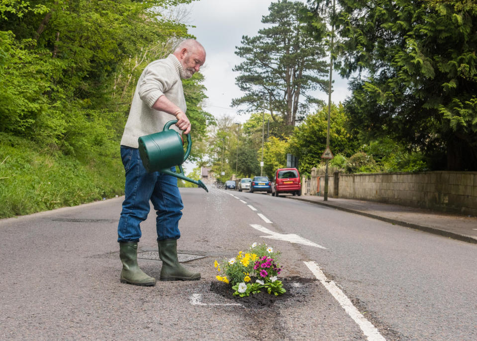 Jason Dorley-Brown at work and watering in a fresh set of flowers in a pothole on Lansdown Road (SWNS)