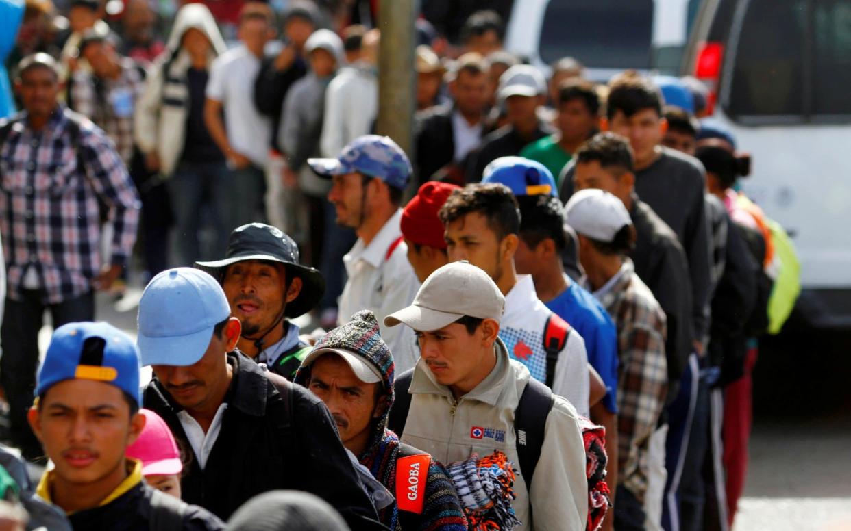 Migrants stand in line for a free meal after arriving in Tijuana - REUTERS