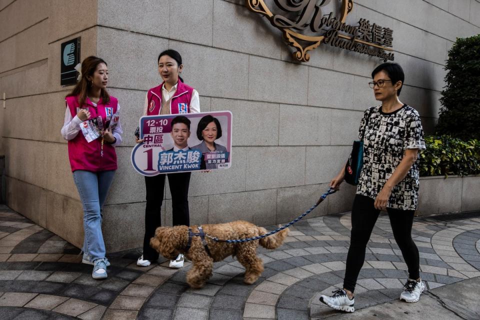 Two women hold a sign for a candidate near a polling station for district elections in Hong Kong on (AFP via Getty Images)