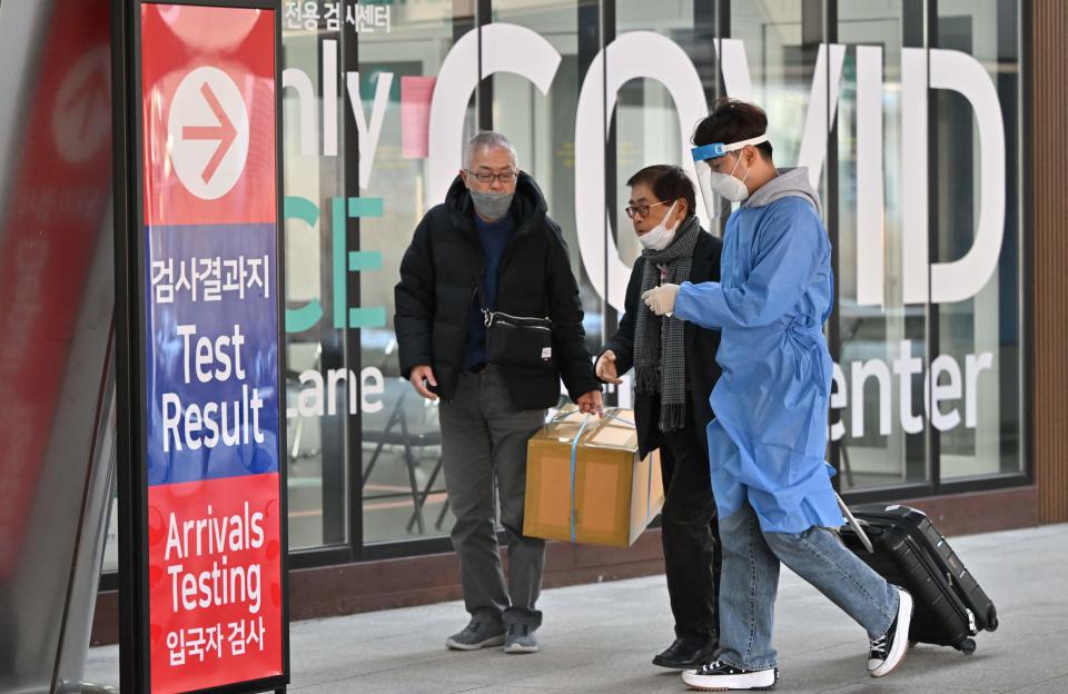 A health worker guides travelers arriving from China in front of a COVID-19 testing center at Incheon International Airport, west of Seoul, South Korea, January 3, 2023. / Credit: JUNG YEON-JE/AFP/Getty