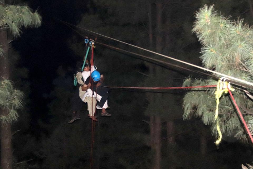 A child is brough to safety along a zip line (EPA)