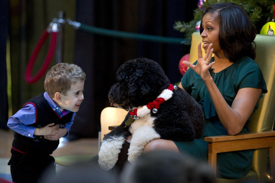 FILE - In this Dec. 14, 2012, file photo A.J. Murray, left, peeks in close at first dog Bo, as first lady Michelle Obama, answers questions from children who are patients at the Children's National Medical Center in Washington. Former President Barack Obama’s dog, Bo, died Saturday, May 8, 2021, after a battle with cancer, the Obamas said on social media. (AP Photo/Jacquelyn Martin, File)