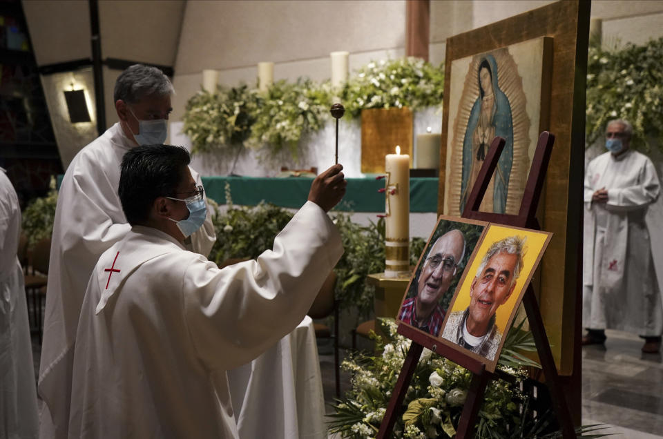 Un sacerdote bendice fotos de los curas jesuitas Javier Campos Morales (izq) y Joaquín César Mora Salazar durante una misa en su honor en una iglesia de la Ciuda de México el 21 de junio del 2022. Los dos religiosos fueron asesinados en una iglesia de una localidad aislada del norte de México. (AP Photo/Fernando Llano)